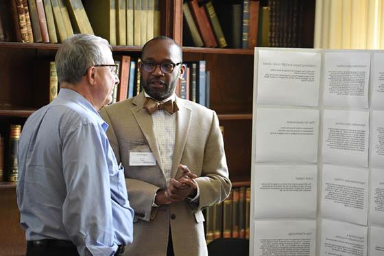 Photo of a man presenting a poster to another man