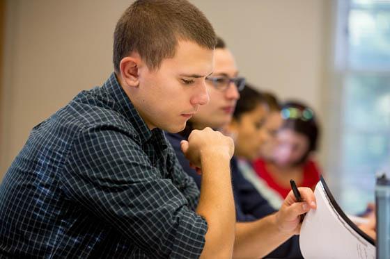 Photo of a male Chatham University paging through notes in a lecture hall